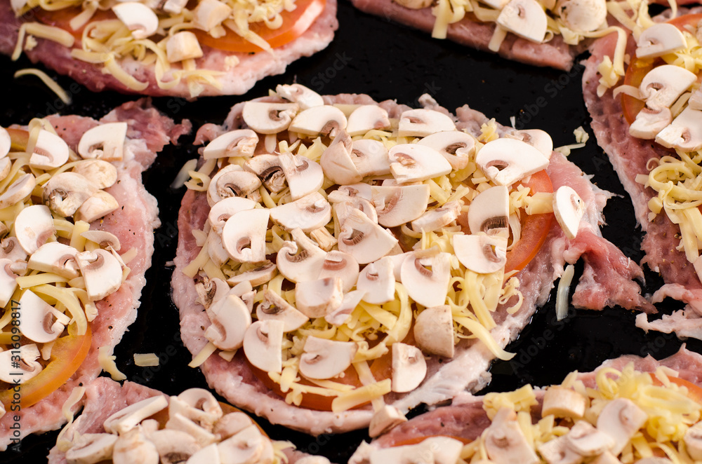 Culinary preparation: chopped pieces of pork, sliced tomatoes, sprinkled with grated cheese and chopped mushrooms Culinary preparation: chopped pieces of pork, sliced tomatoes, sprinkled with grated cheese and chopped mushrooms