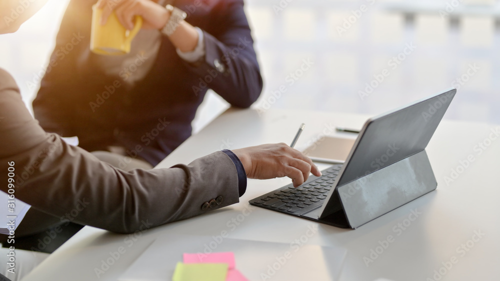 Cropped shot of two businessman consulting on their work with digital tablet Cropped shot of two businessman consulting on their work with digital tablet