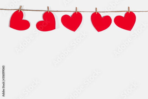 Garland of red hearts on a white isolated background. Natural rope and clothespins. The concept of recognition in love, romantic relationships, Valentine's Day. Copy space