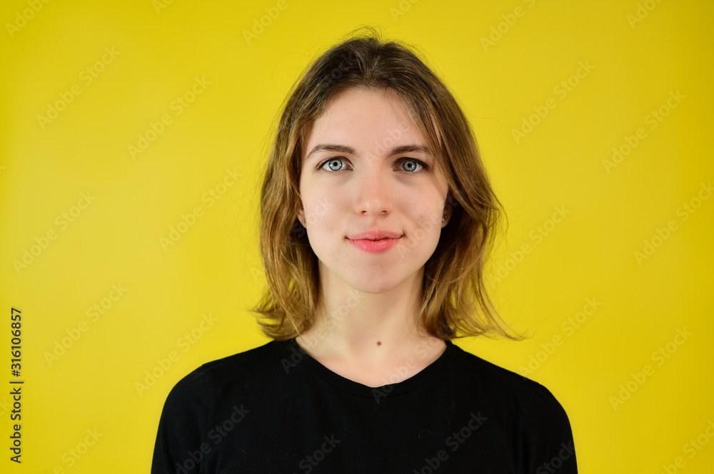 A universal concept, the picture is suitable for any topic. Close-up Studio portrait of a pretty blonde girl in a black T-shirt on a yellow background with bright emotions. A universal concept, the picture is suitable for any topic. Close-up Studio portrait of a pretty blonde girl in a black T-shirt on a yellow background with bright emotions.