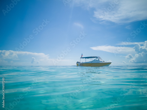 Fototapeta Naklejka Na Ścianę i Meble -  Low angle boat mooring on a turquoise crystal clear water against blue skies.
