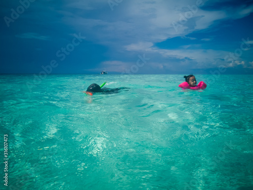People in snorkeling mask dive underwater with tropical fishes in coral reef sea pool. Travel lifestyle, water sports, outdoor adventure, swimming family summer beach holiday with kids