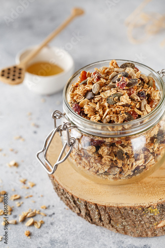 Organic homemade granola cereal with oats, nuts and dried berries. Muesli in a glass jar. Healthy vegan breakfast or snack. Copy space for text. Proper nutrition concept
