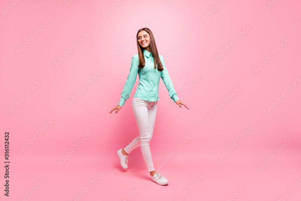 Full body photo of funny pretty lady walking down street enjoy sunny day weather wear specs turquoise shirt white trousers isolated pink color background