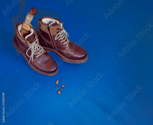 flat lay layout of men's leather accessories. Leather high boots with a knife in the bootleg - a symbol of hunters and brutality, military subjects on a dark blue background - classic blue