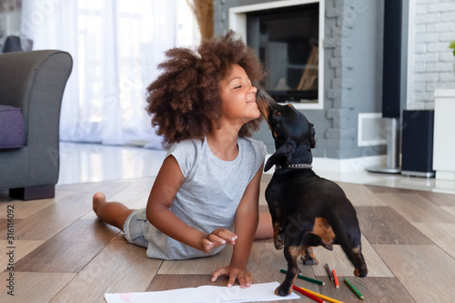 Cute little girl lying on floor playing with dog