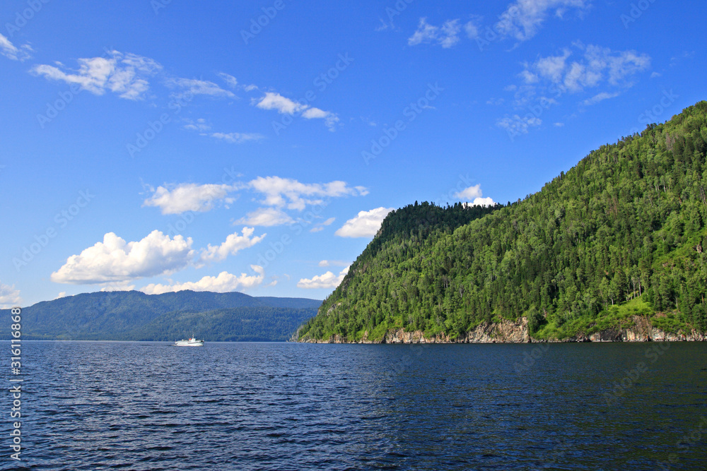Tourist boat on the background of the high shore of lake Teletskoye in Altai in Russia