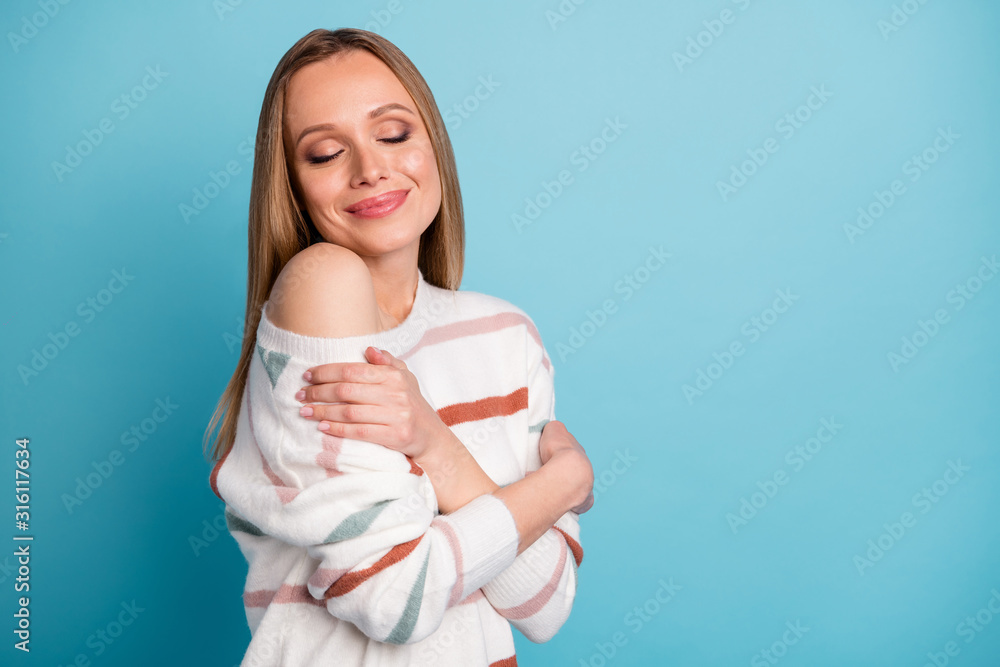 Turned photo of trendy blonde haired fascinating woman hugging herself with eyes closed near empty space enjoying free time isolated pastel color background Turned photo of trendy blonde haired fascinating woman hugging herself with eyes closed near empty space enjoying free time isolated pastel color background