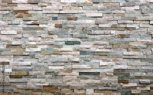 Foto Stone cladding wall made of  striped stacked slabs of natural multicolor rocks
