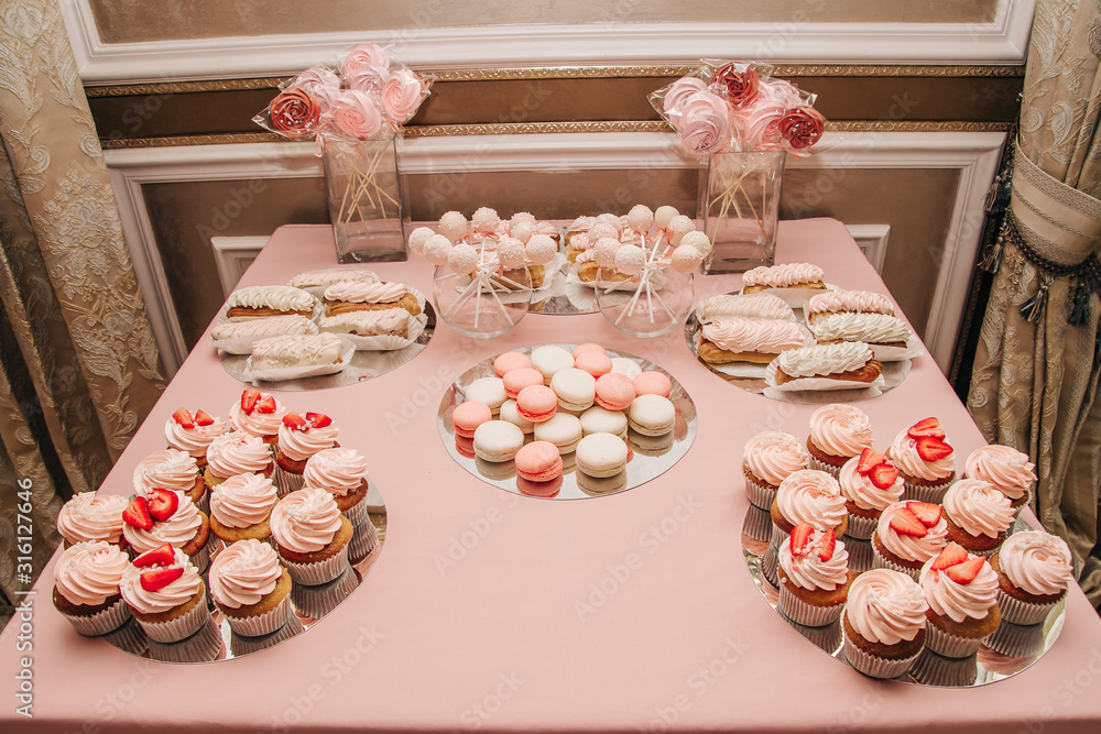 French pastry, eclair, macaroon, cupcakes, meringue, pop cake. Candy bar for a holiday in pink colors.