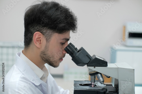 Man in white uniform in laboratory work on analize.