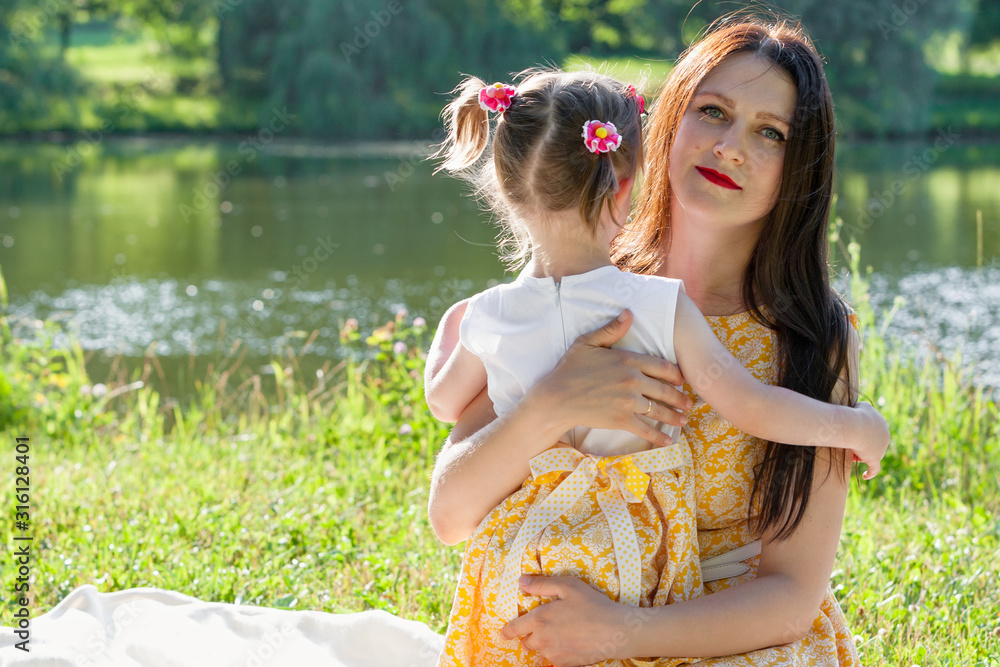 Naklejka premium Mother and daughter in the Park by the lake. A girl embraces a woman.