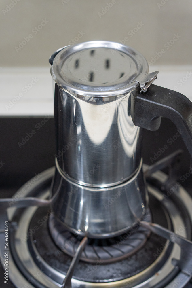 Mokapot coffee brewing on a stove isolated on brown background. Mokapot coffee brewing on a stove isolated on brown background.