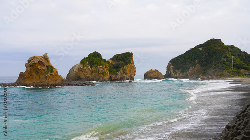 Tropical volcanic beach on the Pacific coast in Japan. black volcanic sand on the beaches of Aburatsu. volcanic rock islands in blue ocean water at sunset