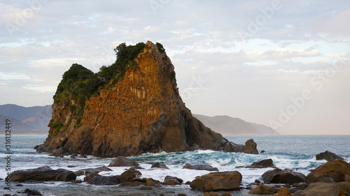 volcanic mountainous islands in the blue water of the Pacific Ocean. tropical islands of Japan overgrown with green plants against a beautiful sunset sky. Aburatsu
