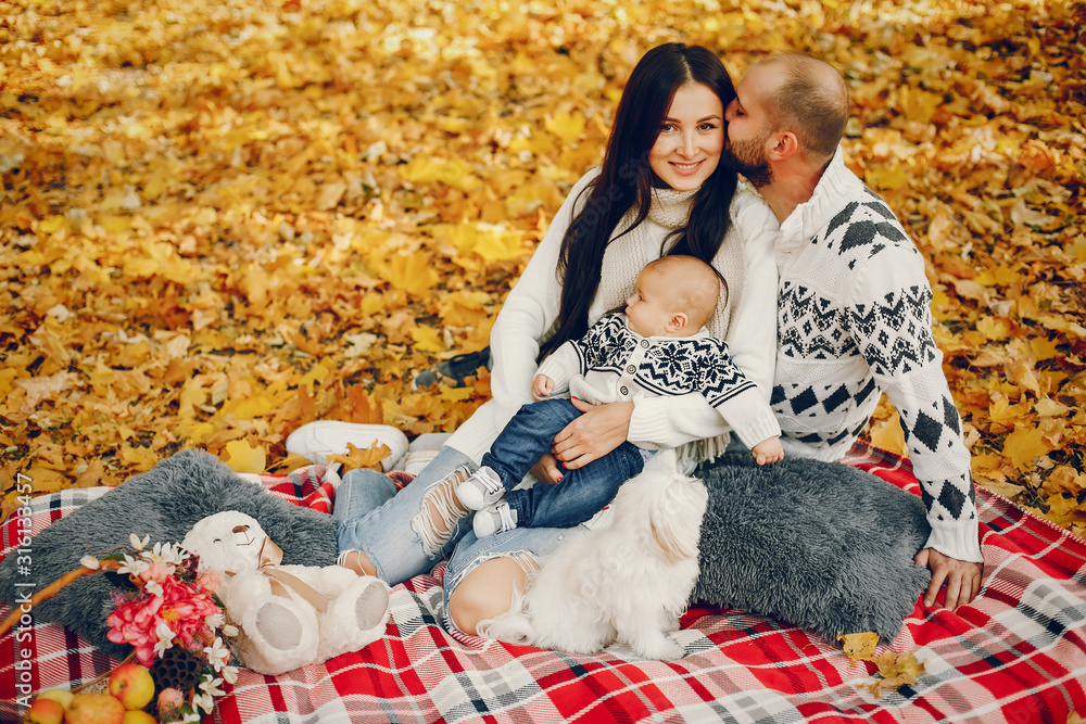Family in a autumn park. Woman in a white sweater. Cute newborn little boy with parents Family in a autumn park. Woman in a white sweater. Cute newborn little boy with parents