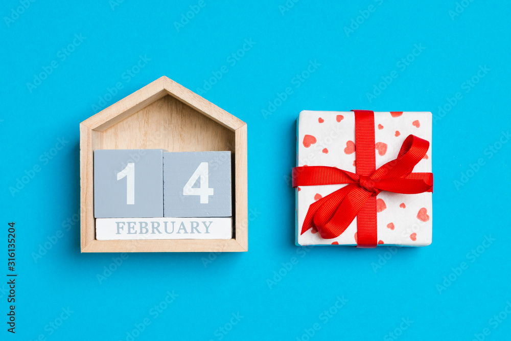 Top view of white gift boxes with hearts and wooden calendar on colorful background. The fourteenth of February. Valentine's Day concept Top view of white gift boxes with hearts and wooden calendar on colorful background. The fourteenth of February. Valentine's Day concept