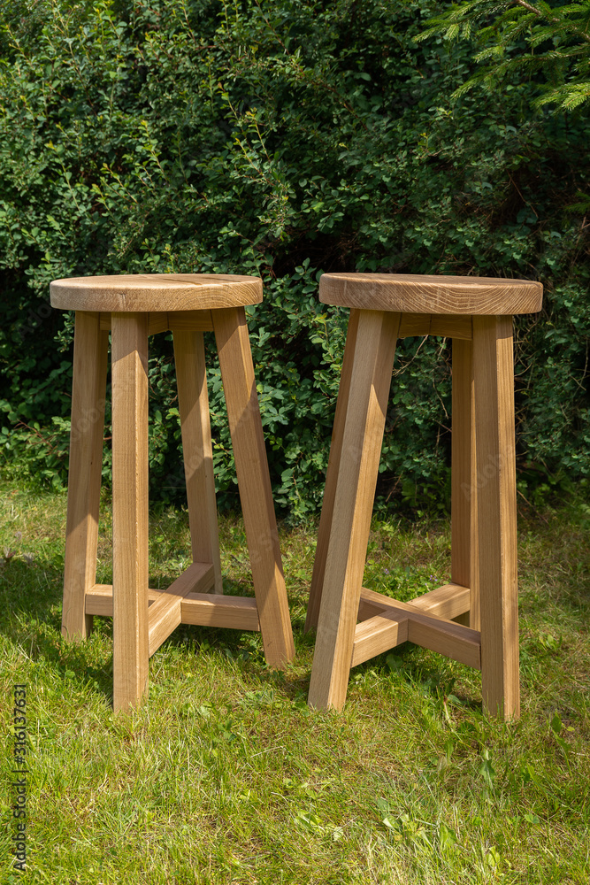 Two kitchen stools, oak against the background of green trees. Two kitchen stools, oak against the background of green trees.