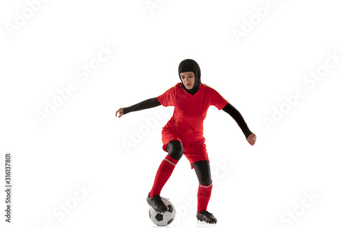 Fototapeta Naklejka Na Ścianę i Meble -  Arabian female soccer or football player isolated on white studio background. Young woman kicking the ball, training, practicing in motion and action. Concept of sport, hobby, healthy lifestyle.