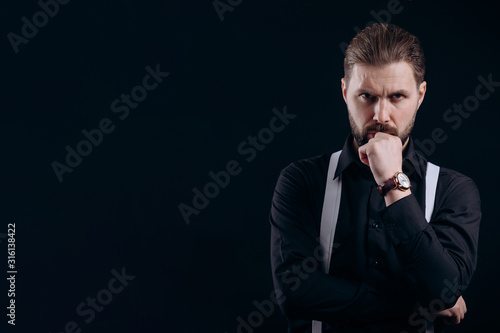 Fotografia, Obraz Thoughtful man in black jacket and white suspenders propping up his chin isolate