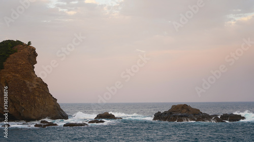 volcanic mountainous islands in the blue water of the Pacific Ocean. tropical islands of Japan overgrown with green plants against a beautiful sunset sky. Aburatsu