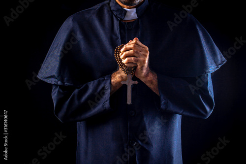Quadro em tela The priest holds the cross on black background For Halloween concepts