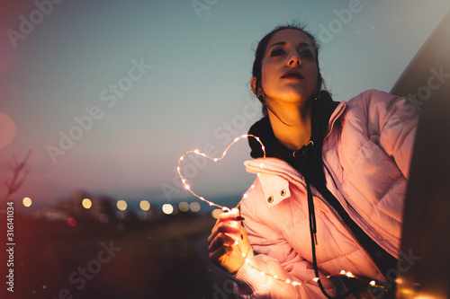 Simbolo del cuore tenuto in mano da una ragazza per San Valentino al tramonto, photo