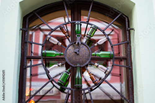 Design of a window grill with a rounded clock made with bottles in Cesky Krumlov  Czech Republic