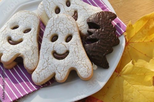 Halloween cookies in shape of a ghost  and bat filled with choocolate on wooden table. Halloween background photo