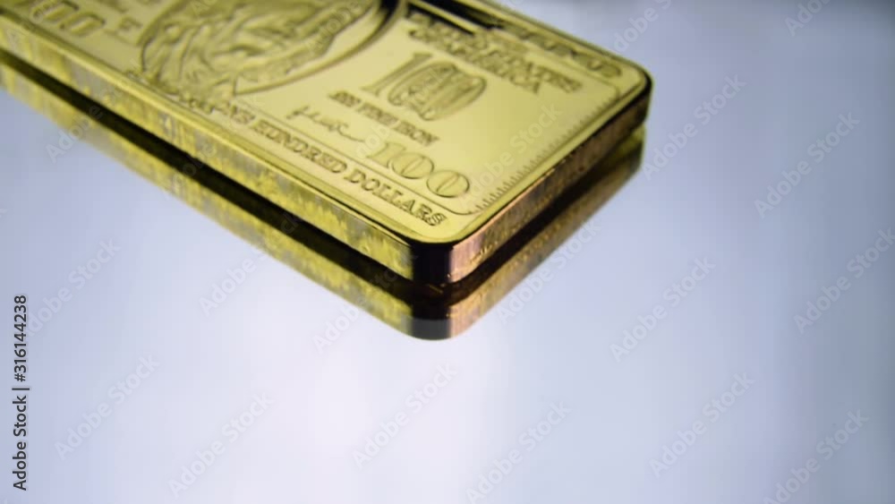 100 hundred dollars gold bar Benjamin Franklin USA America wealth on white surface. Macro. Camera slowly travels above bullion 100 hundred dollars gold bar Benjamin Franklin USA America wealth on white surface. Macro. Camera slowly travels above bullion