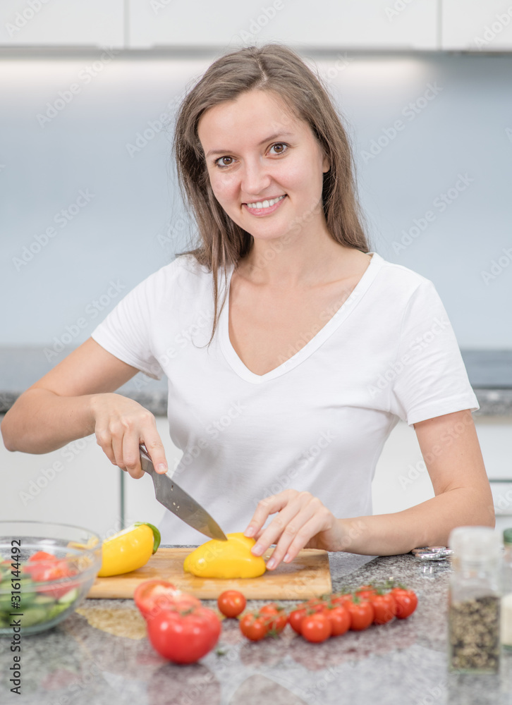 Smiling young woman cooking in the kitchen at home Smiling young woman cooking in the kitchen at home