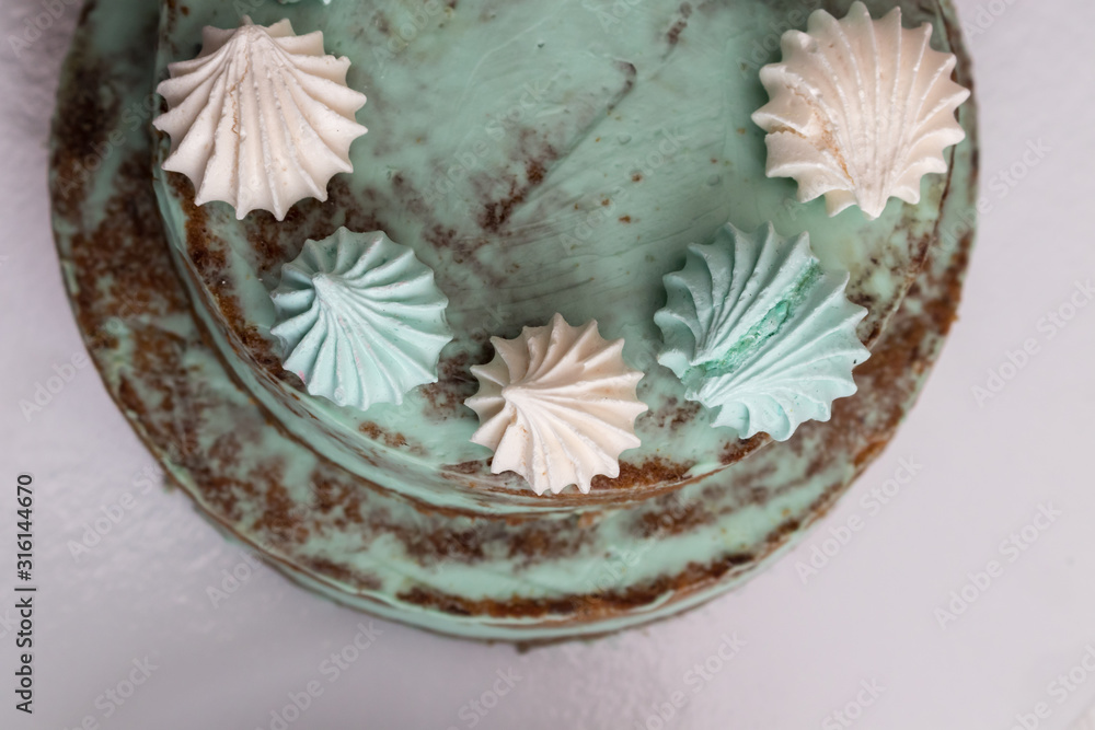 Homemade cake with brown cakes, green cream, decorated with colorful meringues and blueberries Homemade cake with brown cakes, green cream, decorated with colorful meringues and blueberries