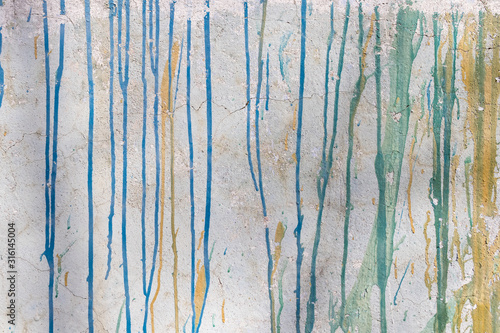Multi-colored streaks of paint on an old white wall