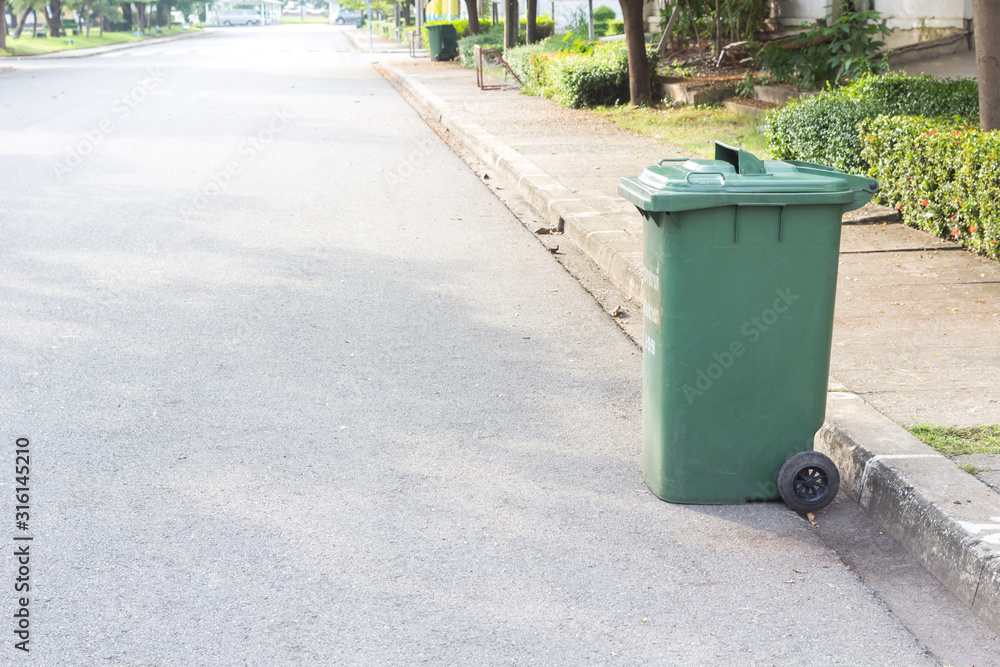large green wheelie bin for rubbish,Public trash background,Big pile of garbage and waiste in black bags. large green wheelie bin for rubbish,Public trash background,Big pile of garbage and waiste in black bags.
