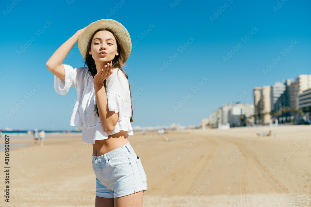girl sends a kiss while standing on a deserted beach