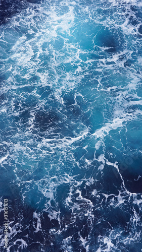 Dark water of the pacific ocean. Natural blue background. foam composition in the ocean. white sea foam, waves, storm. vertical photo