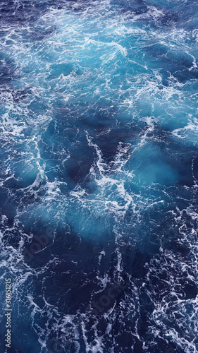 Dark water of the pacific ocean. Natural blue background. foam composition in the ocean. white sea foam, waves, storm. vertical photo