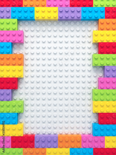Frame of colorful toy bricks on white construction plate