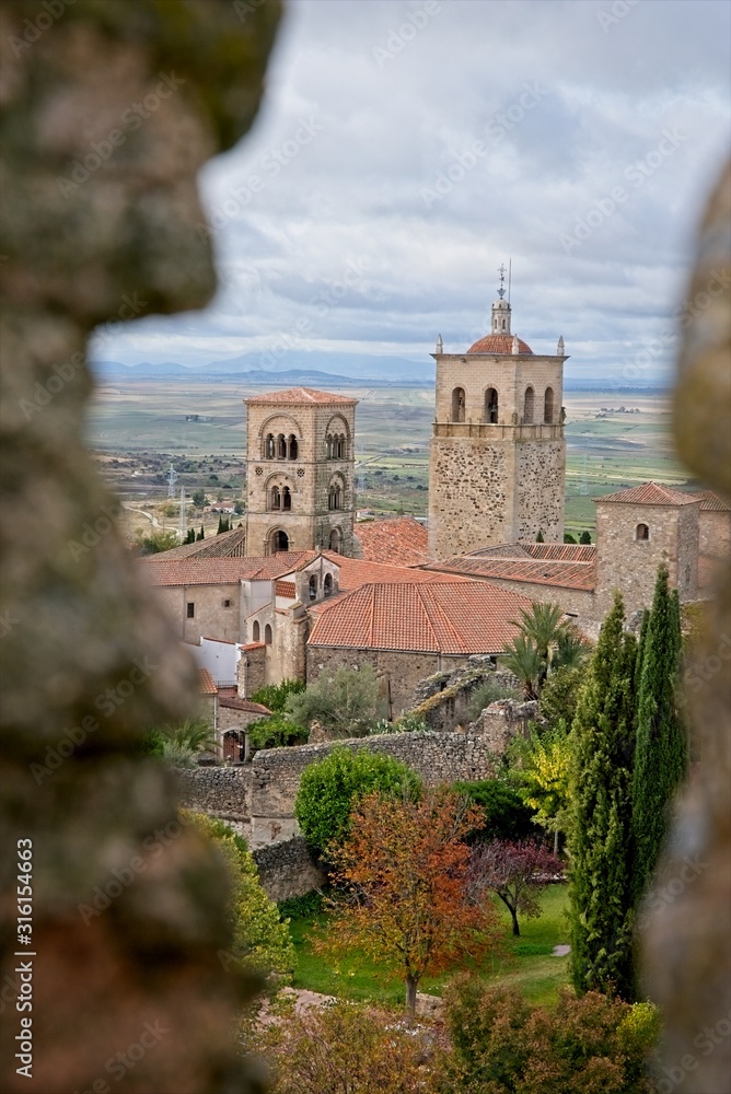 Antique church seen through a hole in the wall of Trujillo, Spain