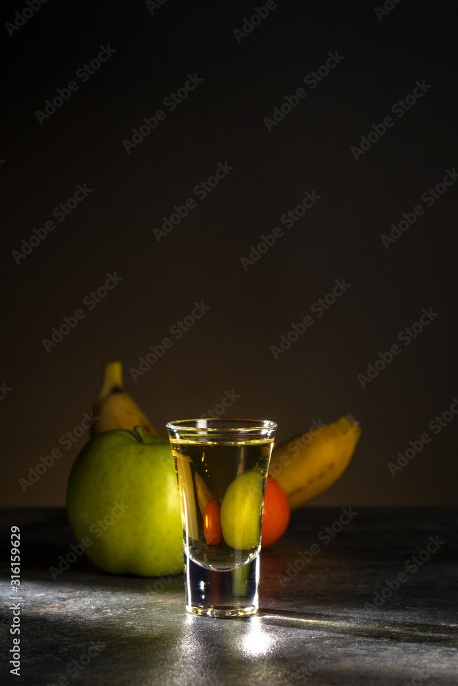 Close-up shot of whiskey and fruit behind it on a beautiful dark brown background. Vertical. Copy space. Close-up shot of whiskey and fruit behind it on a beautiful dark brown background. Vertical. Copy space.