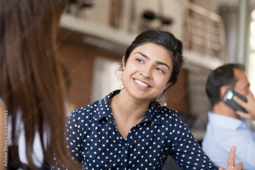 Fotografie Smiling female worker talk with colleague explaining something