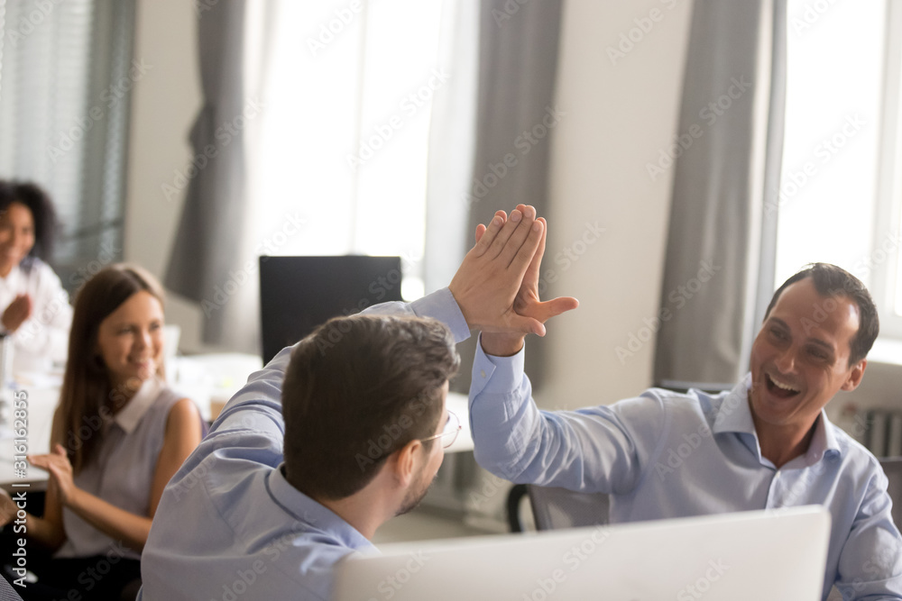 Excited businessmen give high five celebrating shared success Excited businessmen give high five celebrating shared success