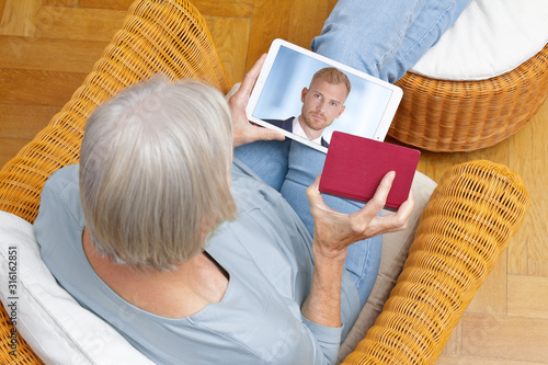 e-id concept: senior woman using a video identification service to open a new bank account with her tablet computer photo