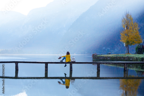 tourist girl in a hat and with a backpack sitting on a wooden bridge