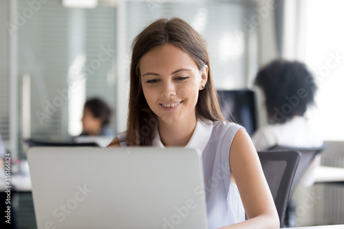 Millennial female employee busy working on laptop in shared office