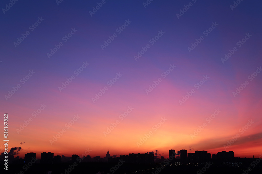 Sunrise over the city, scenic view. Orange sky in soft colors above silhouettes of high-rise buildings, colorful cityscape for background