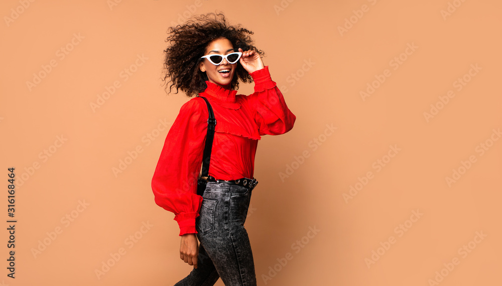Φωτογραφία Horizontal fashion  image of excited black woman jumping with happy face expression on beige background