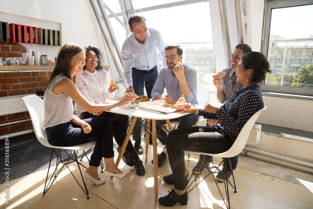 Happy employees eating pizza having fun in office together Happy employees eating pizza having fun in office together