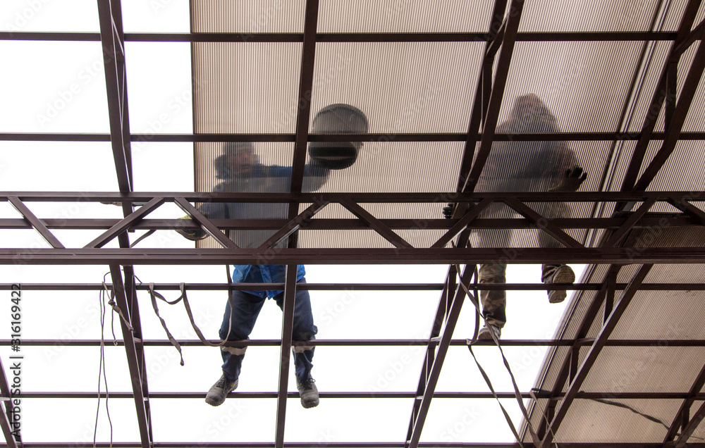 A worker mounts a metal canopy A worker mounts a metal canopy