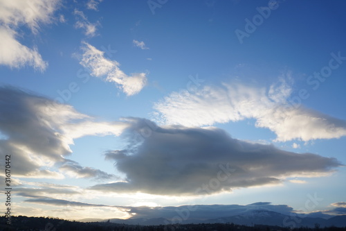 large white fluffy sun-lit clouds against a blue sky. illuminated by direct light from the sun